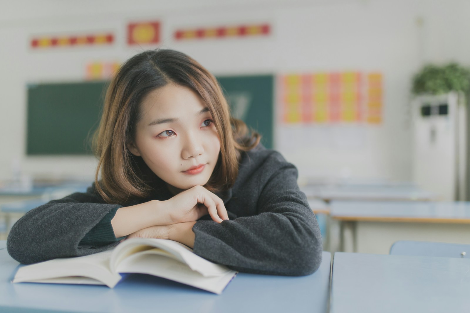 woman in gray dress resting her hands on white table, studying for the TOEFL