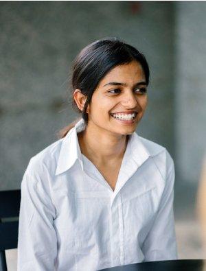 Portrait of a young Asian Indian woman in a job interview. She is confident, relaxed and smiling as she sits in an office during the day and talks with her interviewees.